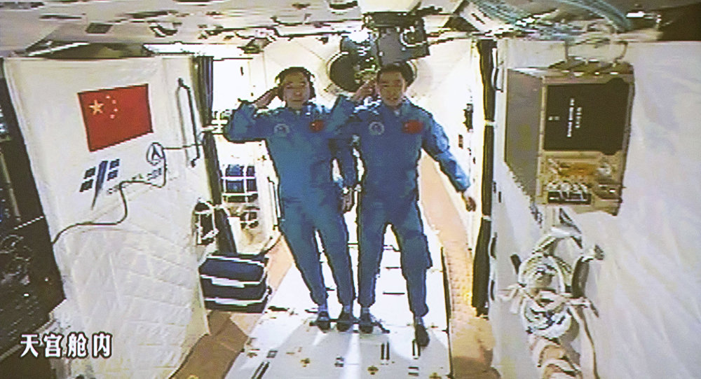 In this image taken off the screen at the Beijing Aerospace Control Center on Wednesday, Oct. 19, 2016 and released by Xinhua News Agency, two Chinese astronauts Jing Haipeng, left and Chen Dong salute in the space lab Tiangong 2